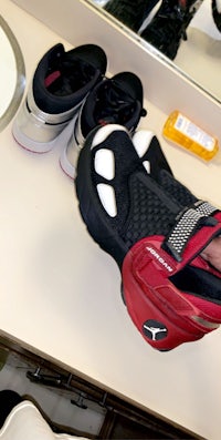 a person holding a pair of shoes in front of a sink